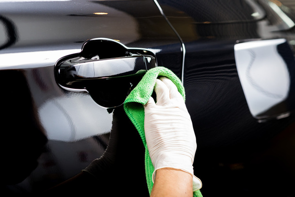 Auto detaillering serie: werknemer zwarte auto schoonmaken - Foto, afbeelding