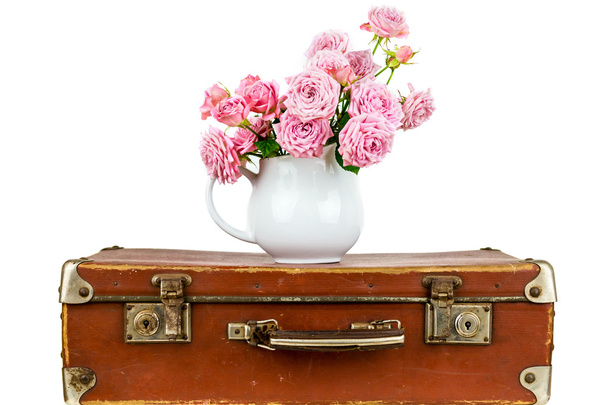 Růžové květy v džbánu na staré hnědé vinobraní kufr. - Fotografie, Obrázek