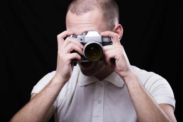 ένας νεαρός άνδρας που κοιτώντας το φακό του μια παλιά φωτογραφική μηχανή - Φωτογραφία, εικόνα