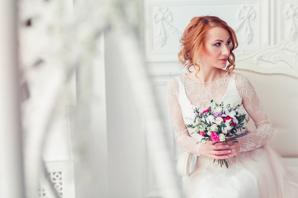 красивая невеста со свадебным букетом сидит на кровати с копией
  - Фото, изображение