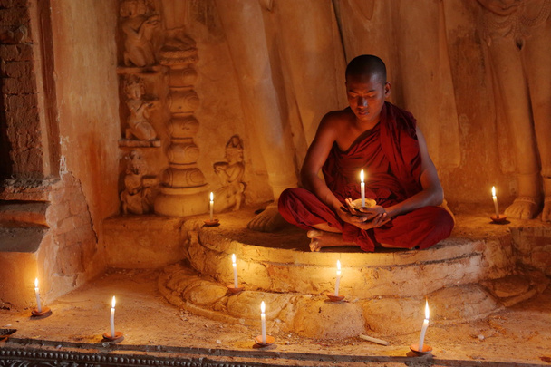 Boeddhistische monnik in gebed bij kaarslicht - Foto, afbeelding