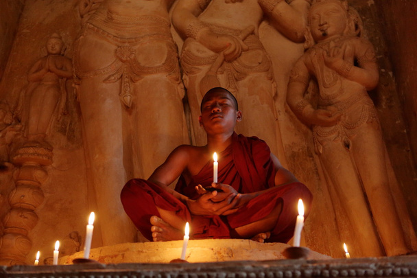 Moine bouddhiste à la prière aux chandelles
 - Photo, image