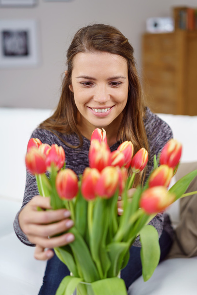 Pretty young woman arranging a vase of flowers - Foto, Imagen