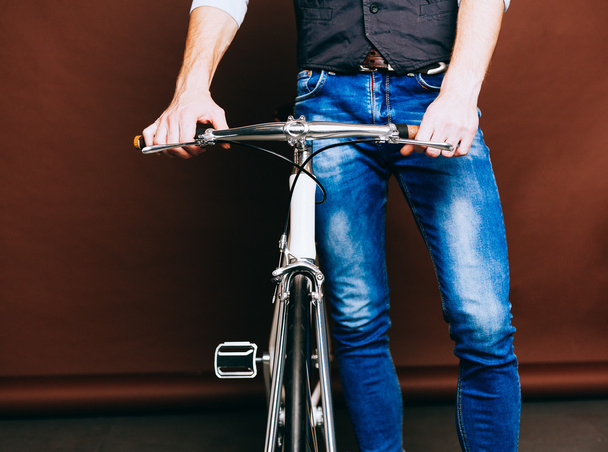 Indoor portrait of young fashion handsome hipster man with vintage bike. Warm color. Close up. - Foto, imagen