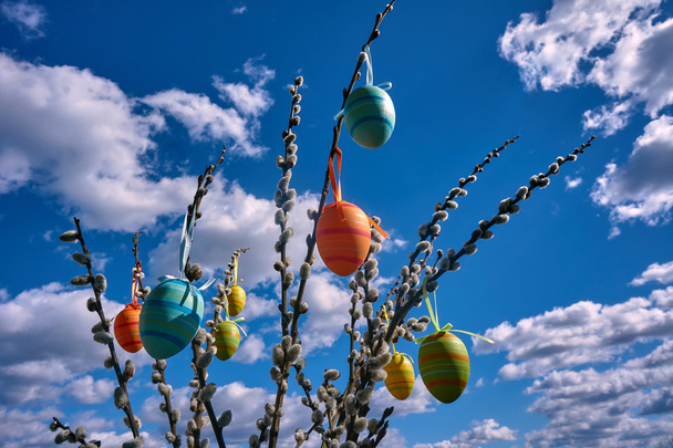 Ovos de Páscoa pendurados em pepinos contra o céu
 - Foto, Imagem