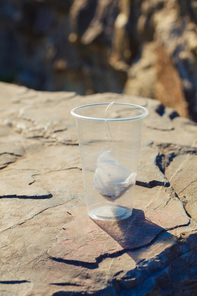 bolsa de té en una taza de plástico desechable en una roca en la naturaleza de nuevo
 - Foto, Imagen