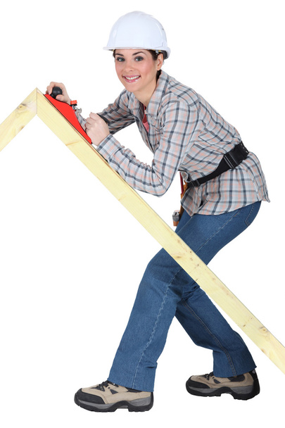 Tradeswoman using a plane to smooth a wooden frame - Photo, image