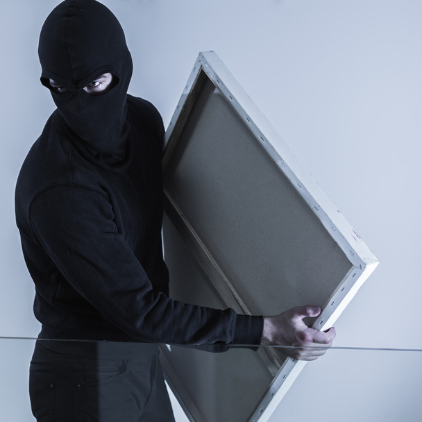 Masked criminal holding stolen picture - Фото, зображення