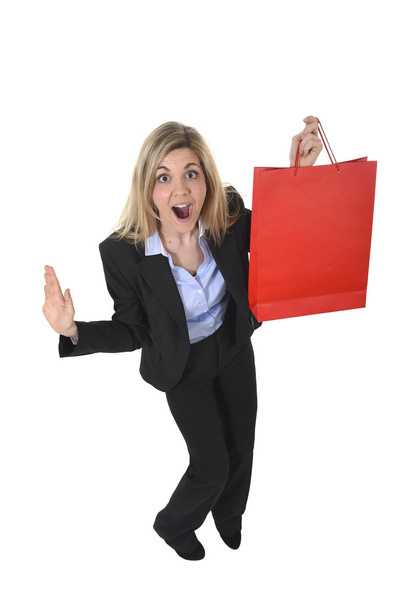 młody szczęśliwy piękna kobieta w biznesie garnitur w wyrazem twarzy podekscytowany gospodarstwa czerwoną torbę na zakupy - Zdjęcie, obraz