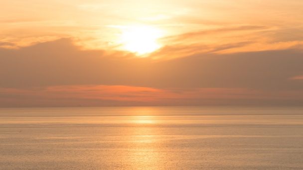 海の上に美しい柔らかいオレンジ色の空をぼかす。背景に夕日。抽象的なオレンジ色の空。夕焼けの背景に劇的な黄金の空. - 写真・画像