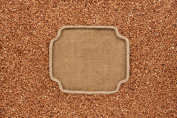 Figured frame made of rope with buckwheat grains on sackcloth - Фото, изображение