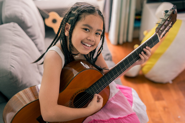 Feliz chica sonriente aprendiendo a tocar la guitarra acústica
 - Foto, imagen