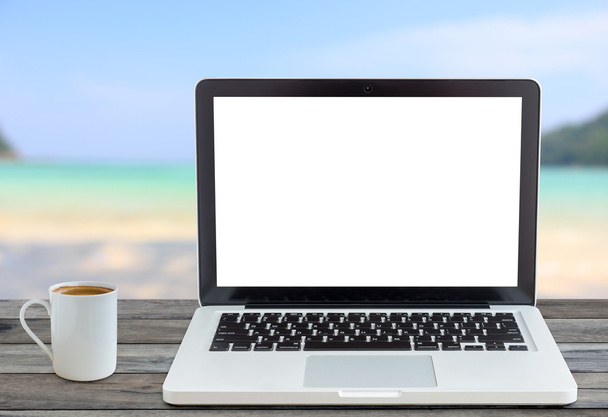 laptop computer en koffie kopje voorste hoek op uitzicht op het strand - Foto, afbeelding