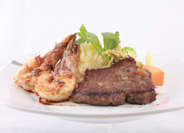ein Steak und Shrimp Dinner über einer karierten Tischdecke - Foto, Bild