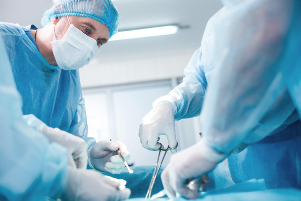 Experienced surgical doctor is operating on a patient - Foto, afbeelding