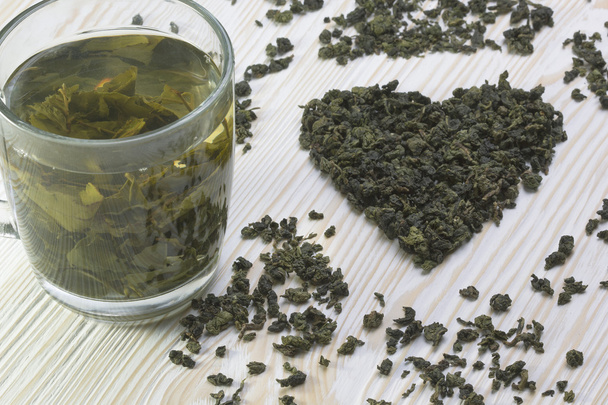 Zielona herbata liść w kształcie serca, na tle drewniany kubek - Zdjęcie, obraz