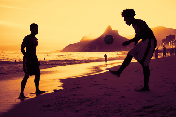 zwei Personen spielen Fußball am Strand von Rio bei Sonnenuntergang - Foto, Bild