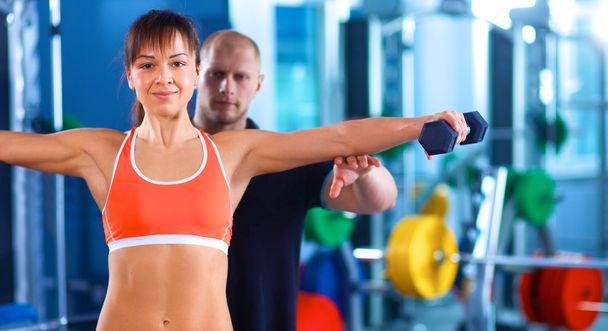 Beautiful woman at the gym exercising with her trainer - Photo, image
