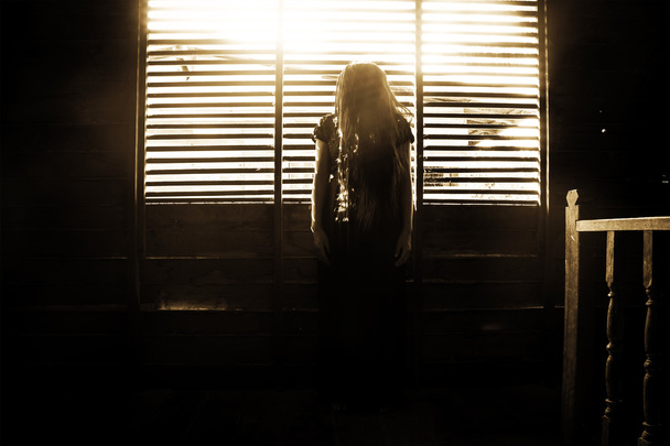 Μυστηριώδες κορίτσι σε μαύρο φόρεμα που στέκεται εγκαταλειφθεί σπίτι - Φωτογραφία, εικόνα