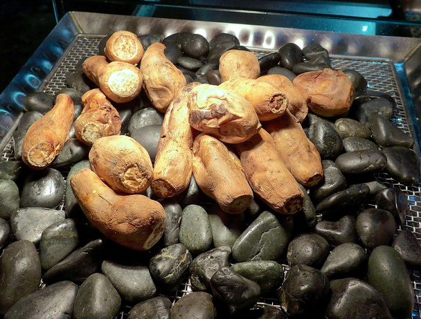 Patata dulce asada sobre piedras
 - Foto, Imagen