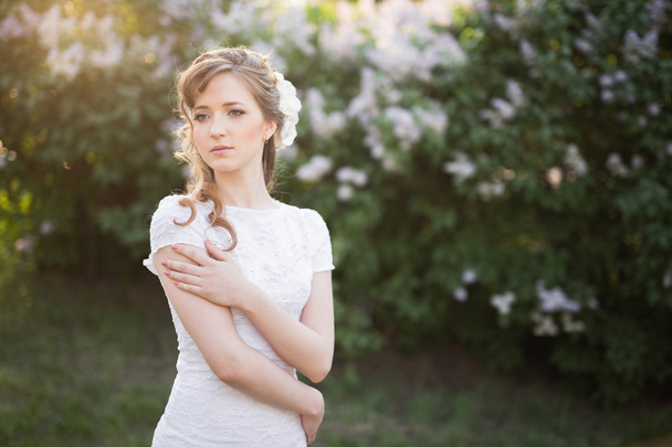 Bride in white dress embracing herself while looking away - Foto, imagen