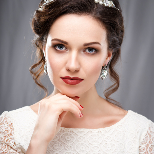 Κομψή νεαρή γυναίκα με τέλειο μακιγιάζ και στυλ μαλλιών σε ένα λευκό φόρεμα. Ομορφιά μόδας πορτρέτο με αξεσουάρ - Φωτογραφία, εικόνα