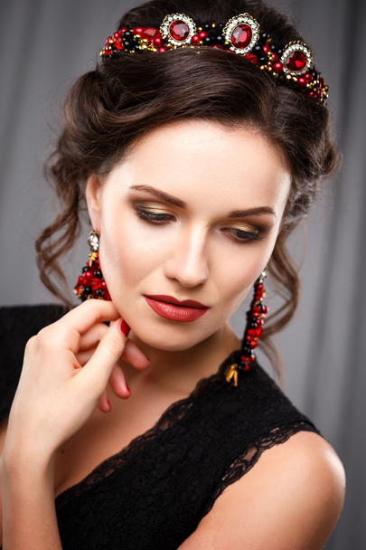 Elegant young woman with perfect makeup and hair style in a black dress with diadem and earrings. Beauty fashion portrait with accessories - Photo, Image