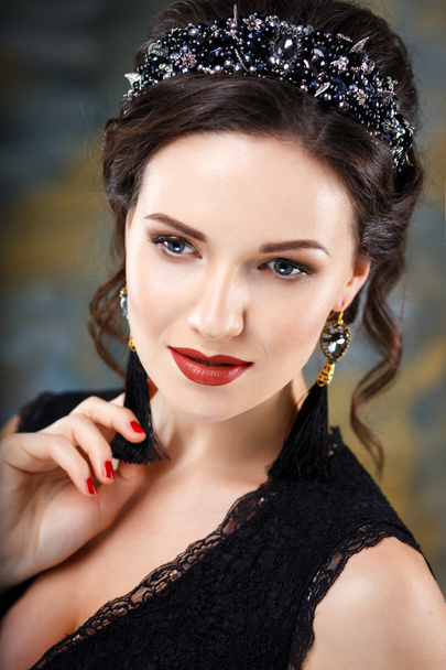 Elegant young woman with perfect makeup and hair style in a black dress with diadem and earrings. Beauty fashion portrait with accessories - Foto, Imagen