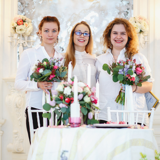 two young women holds a bouquet they made and their teacher florist. Decor and floral composition on a table. - Fotografie, Obrázek