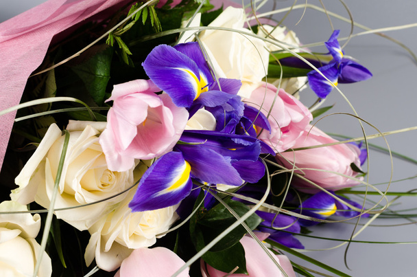 Delicate beautiful bouquet of  iris, roses and other flowers on gray background - Photo, Image