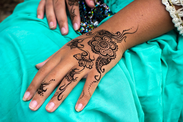 Vrouwelijke handen met henna tattoo mehndi op lichte blauwe jurk - Foto, afbeelding