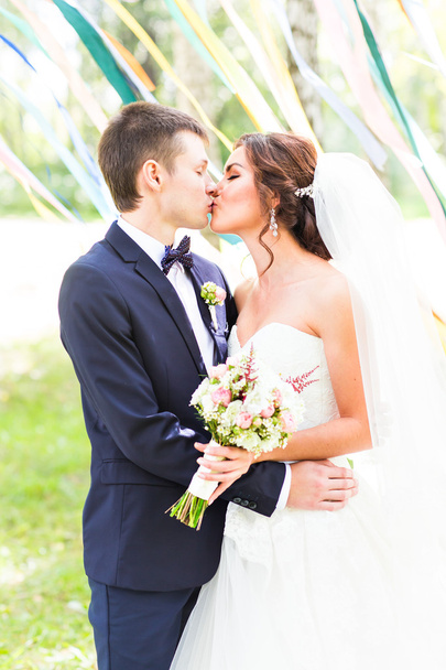 couple de mariage embrasser, mariée tenant un bouquet de fleurs, marié embrassant son
 - Photo, image
