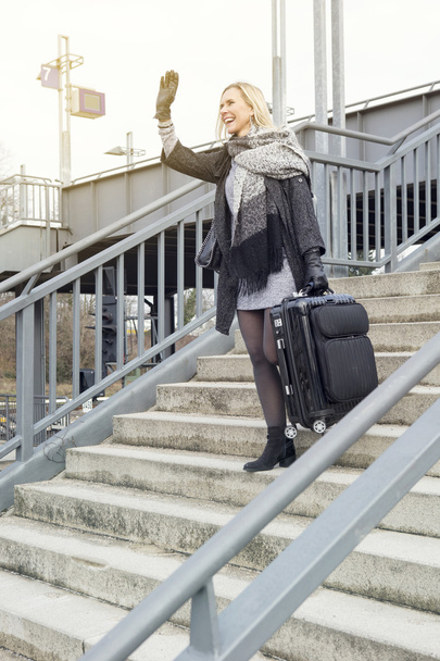 woman with suitcase walking down stairs at train station - Photo, Image