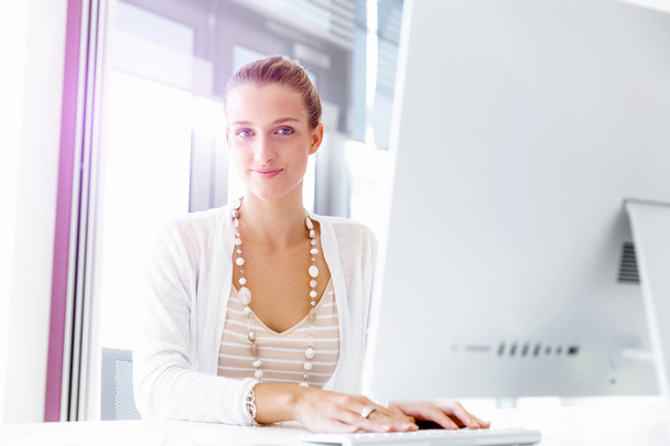 Attractive office worker sitting at desk - Photo, image
