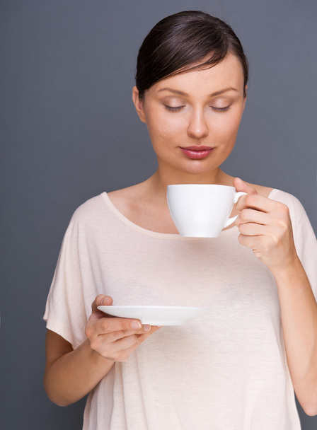 Portrait of young fashionable woman giving hot coffee or tea beverage - Foto, afbeelding