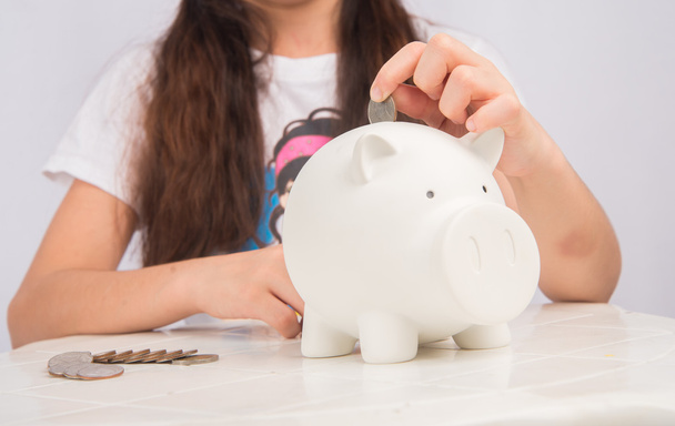 Menina economizando dinheiro no banco porquinho
 - Foto, Imagem