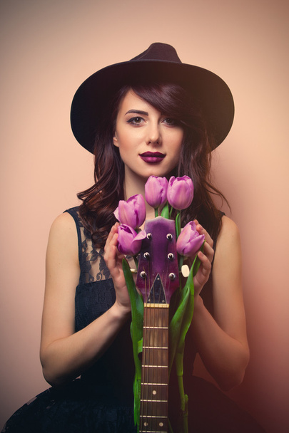 πορτρέτο του μια νεαρή όμορφη γυναίκα με κιθάρα και τουλίπες - Φωτογραφία, εικόνα