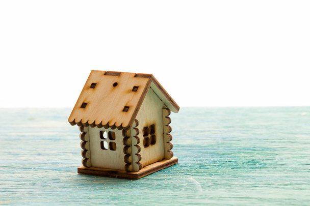 Spielzeug Holz Modellhaus als Symbol Familie und Liebe Konzept auf sonnigem alten blauen Holzgrund Kauf eines Hauses, Hypothek, Reparatur, Stabilität - Foto, Bild