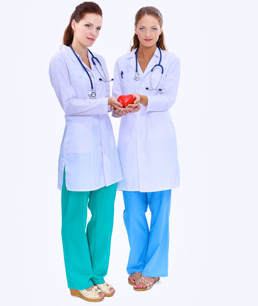 Two woman doctor holding a red heart, isolated on white background - Foto, Imagem