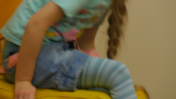 El niño está sentado y balanceándose sobre una almohada se quita caminando Pequeña rubia con medias rayadas está jugando con almohadas amarillas en forma de cubo Sala de juegos
 - Metraje, vídeo
