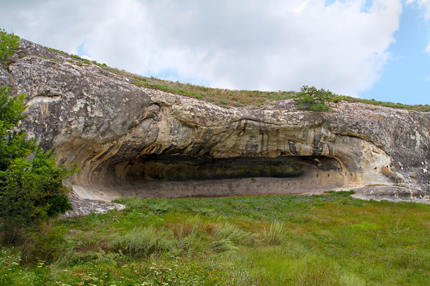 The elongated oval grotto in the rock and surrounded by the brig - Photo, Image
