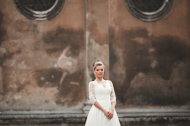 Wonderful bride with a luxurious white dress posing in the old town - Foto, afbeelding