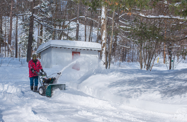 A man in work clothes, hat and gloves, operating a snow thrower / blower on a winter day in Canada. - Photo, Image
