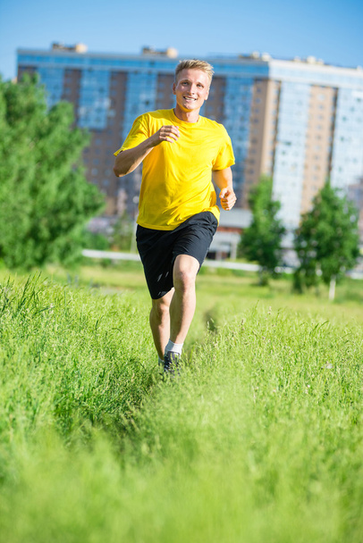 Sporty man jogging in city street park. Outdoor fitness. - Zdjęcie, obraz