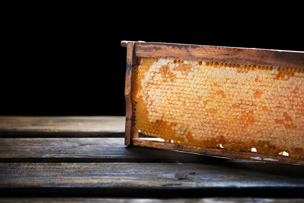 Quadro de madeira com favo de mel cheio de mel, isolado em preto
 - Foto, Imagem