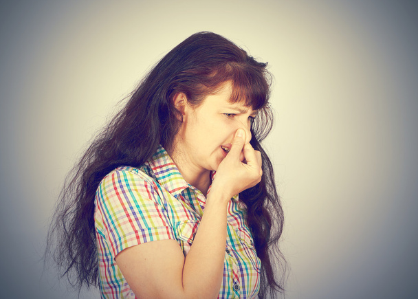 νέα γυναίκα που κρατά τη μύτη λόγω δυσάρεστη μυρωδιά. - Φωτογραφία, εικόνα