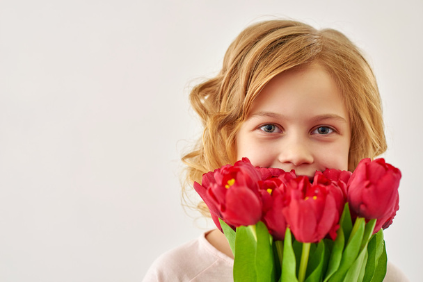 Cute little girl holding the bunch of flowers - Фото, изображение
