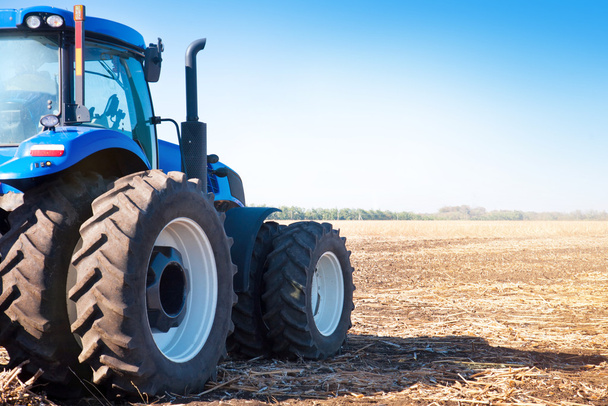 Синий трактор на фоне пустого поля
  - Фото, изображение