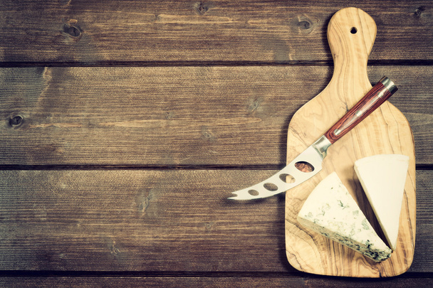 Сыр и нож лежат на деревянном столе
 - Фото, изображение