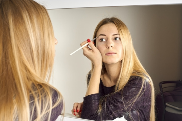 woman does makeup before a mirror - Zdjęcie, obraz